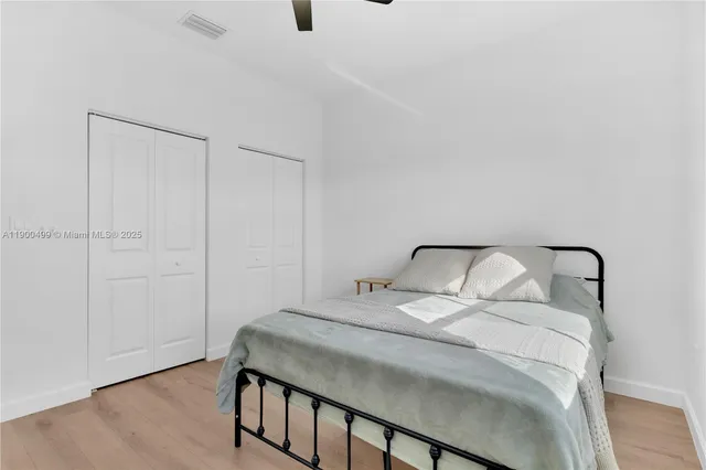 a view of an empty room with wooden floor and a ceiling fan