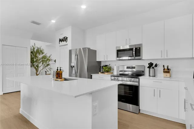 a kitchen with stainless steel appliances a refrigerator sink and white cabinets