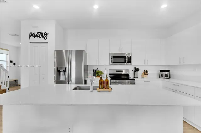 a kitchen with a refrigerator a stove and white cabinets