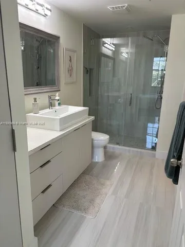 a spacious bathroom with a sink a toilet a mirror and shower