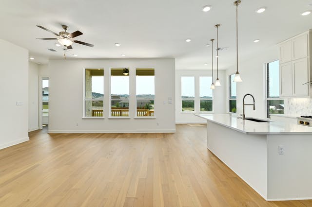 19005 Fernando Trail Austin, TX 78738 - Photo 25 of 26 Kitchen featuring white cabinetry, an island with sink, light wood finished floors, hanging light fixtures, and open floor plan