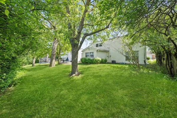 a view of white house with a tree in a yard