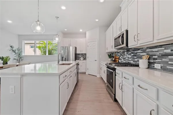 a kitchen with kitchen island granite countertop lots of white stainless steel appliances and white cabinets