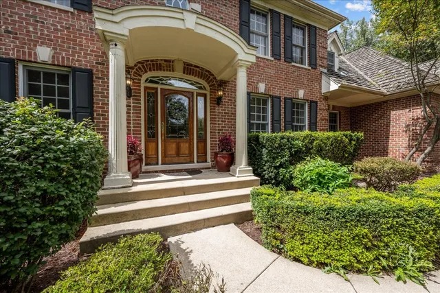 a view of a brick house with plants and large tree