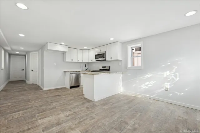 a view of kitchen with kitchen island a sink wooden floor and a refrigerator