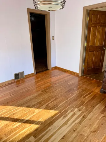 a view of an empty room with wooden floor