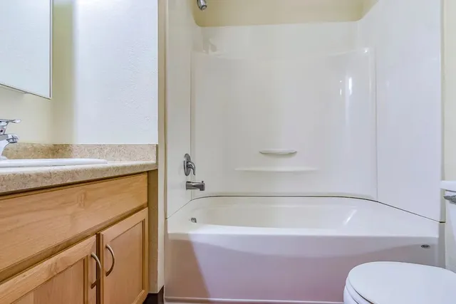 a view of a kitchen that shows a stove top oven a sink and a dishwasher with wooden floor