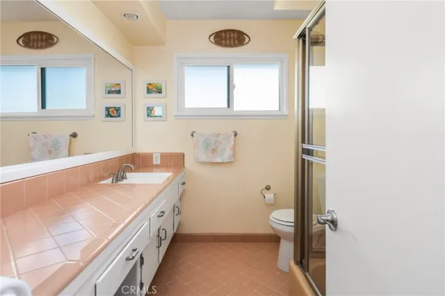 a bathroom with a granite countertop sink a large mirror and a toilet