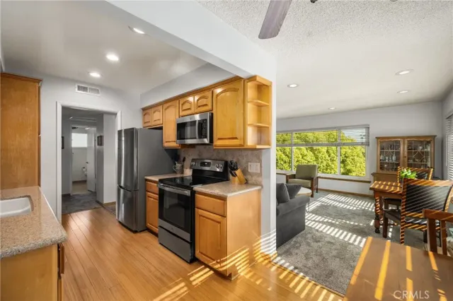 a view of a kitchen with furniture a ceiling fan and wooden floor