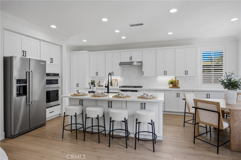 3 Tudor Way Ladera Ranch, CA 92694 - Photo 6 of 25 a kitchen with a sink a refrigerator and chairs