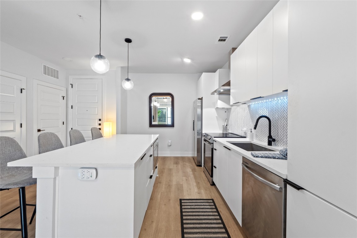 a kitchen with a sink a counter top space stainless steel appliances and cabinets