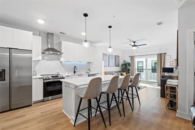 a kitchen with stainless steel appliances a dining table chairs stove and refrigerator