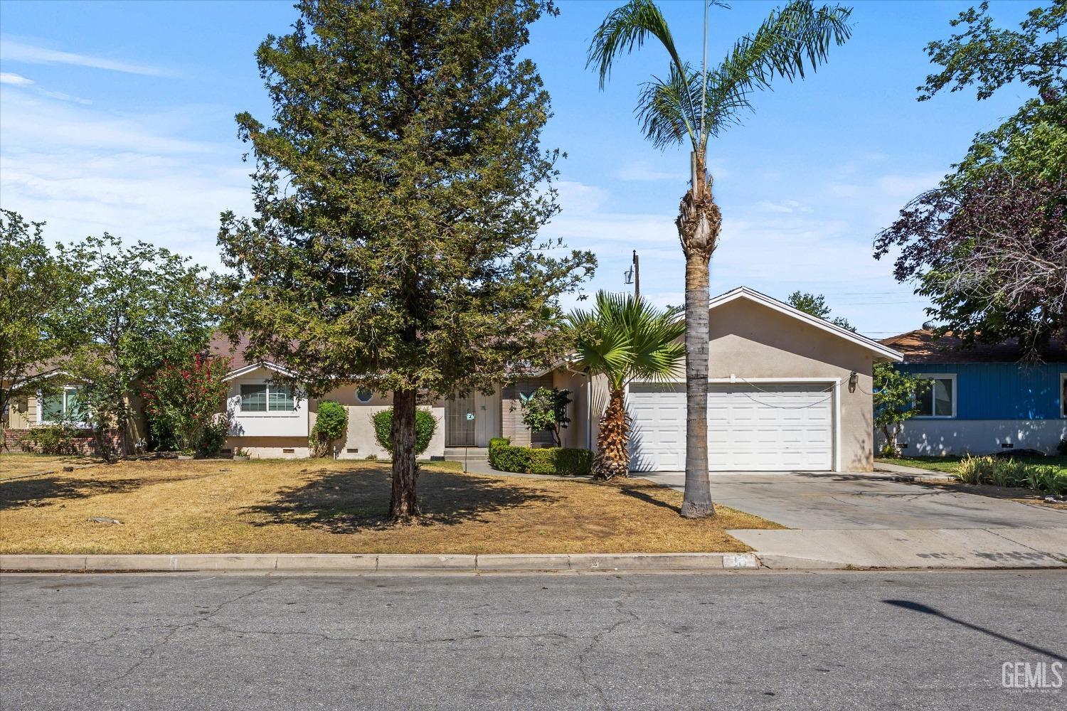 Undisclosed Address Bakersfield, CA 93309 - Photo 2 of 32 a front view of a house with a yard and palm trees