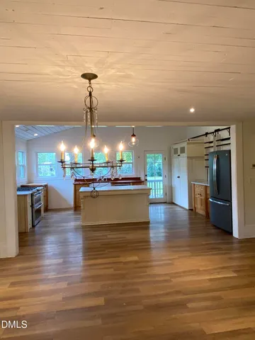 a view of a living room with kitchen island stainless steel appliances wooden floor and living room view