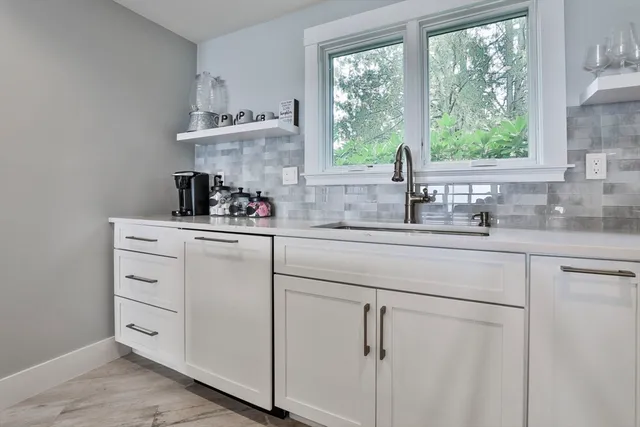 a kitchen with white cabinets and window