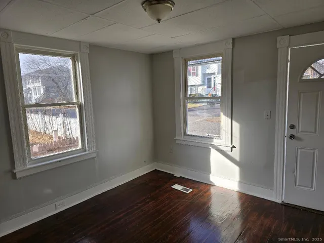 a view of an empty room with wooden floor and a window