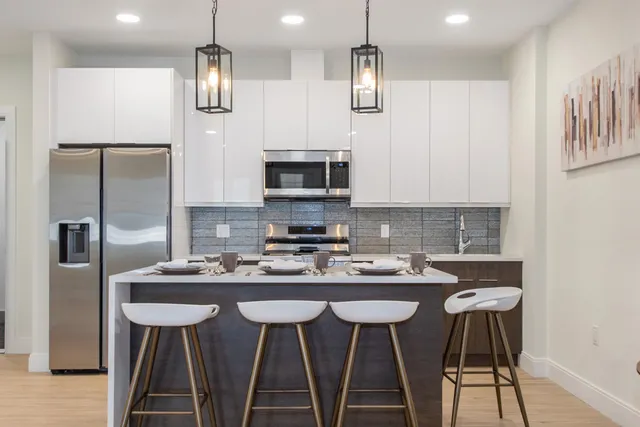 a kitchen with stainless steel appliances granite countertop a sink a stove a refrigerator and white cabinets with wooden floor