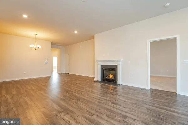 a view of an empty room with wooden floor and a fireplace