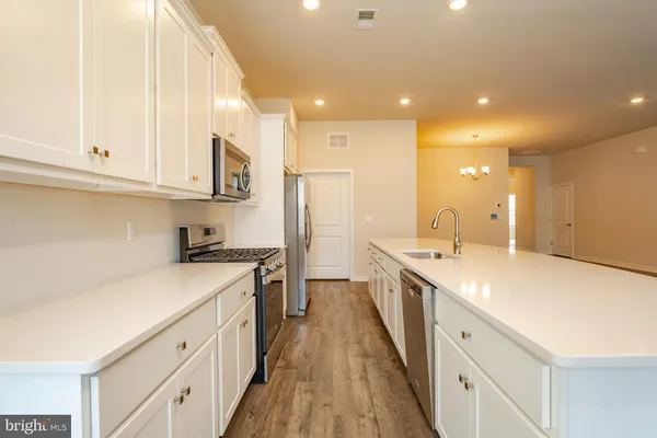 a large kitchen with stainless steel appliances granite countertop a lot of counter space and wooden floors