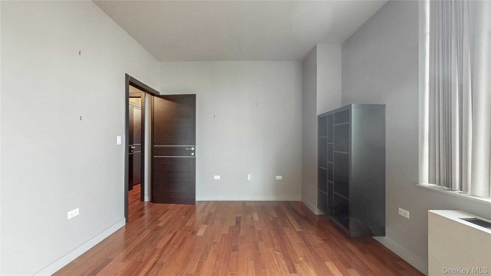 10724 71st Road, Unit 7E Queens, NY 11375 - Photo 15 of 21 Unfurnished bedroom with light wood-type flooring and radiator heating unit