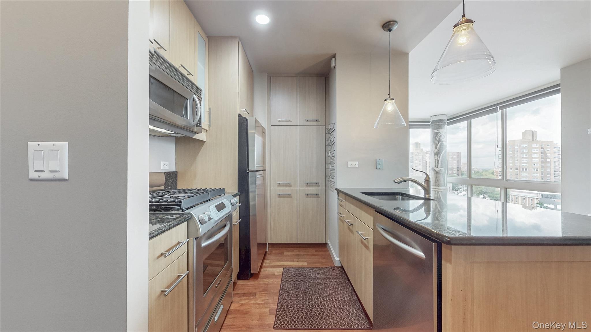 10724 71st Road, Unit 7E Queens, NY 11375 - Photo 4 of 21 Kitchen with dark stone counters, stainless steel appliances, light wood-type flooring, hanging light fixtures, and modern cabinets