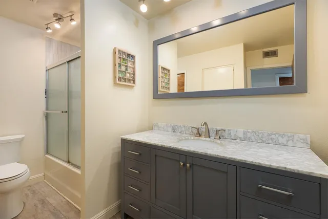 a bathroom with a granite countertop sink toilet and mirror