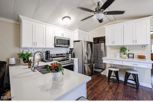 a kitchen with stainless steel appliances a stove a refrigerator a sink a stove a dining table and chairs with wooden floor