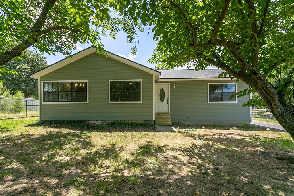 Ranch-style residence featuring green horizontal siding, a dark roof, white trim windows, and a white front door