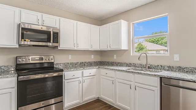 a kitchen with granite countertop white cabinets and appliances
