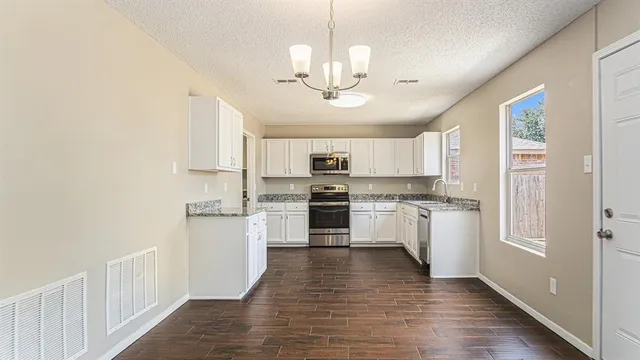 a large kitchen with cabinets wooden floor and stainless steel appliances