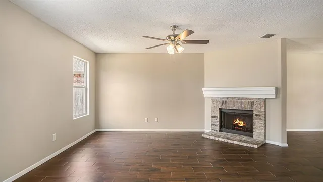 a view of an empty room with wooden floor and a fireplace