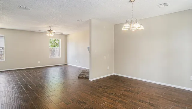 a view of empty room with wooden floor and chandelier