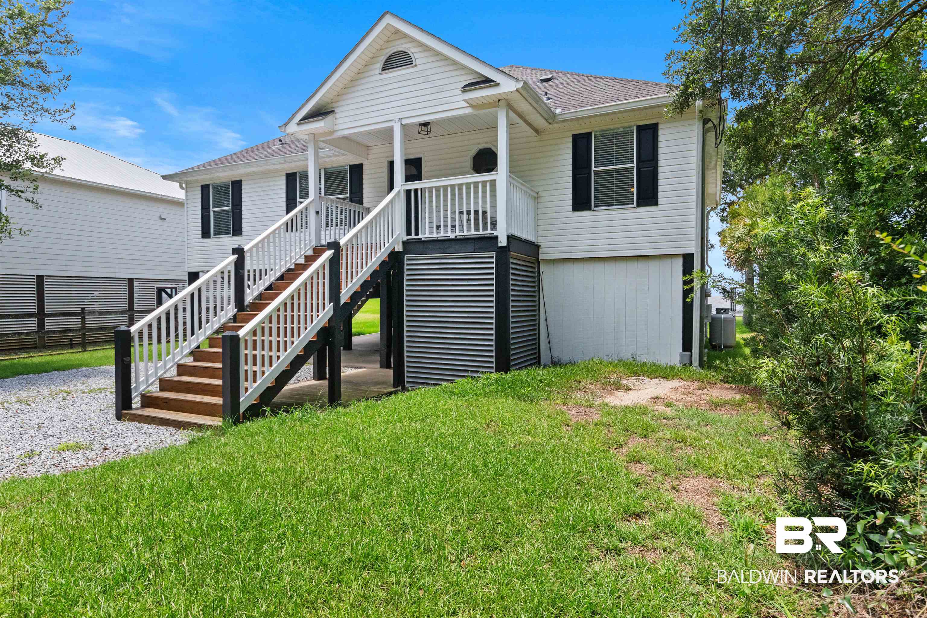 9581 South Bay Street Foley, AL 36535 - Photo 6 of 44 Elevated white-sided residence featuring a covered front porch with white railings and dual staircases