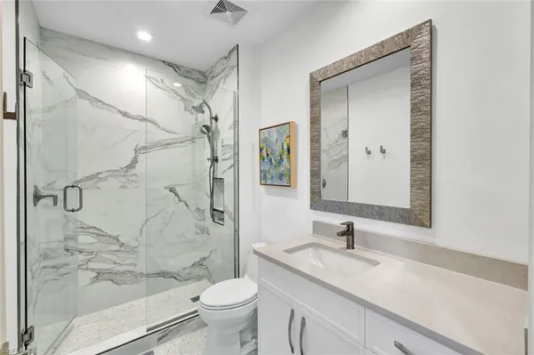 a bathroom with a granite countertop sink toilet and shower