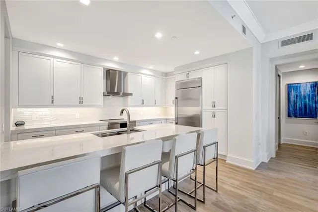 a large white kitchen with a sink and dishwasher a stove with wooden floor