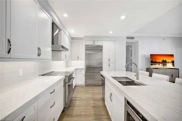 a kitchen with a sink white cabinets and stainless steel appliances