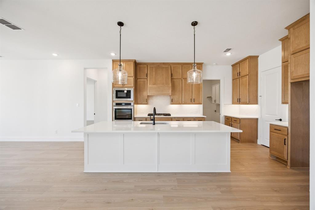 3412 Aldrich Road McKinney, TX 75071 - Photo 14 of 38 a view of a kitchen with stainless steel appliances granite countertop a stove and a wooden floor