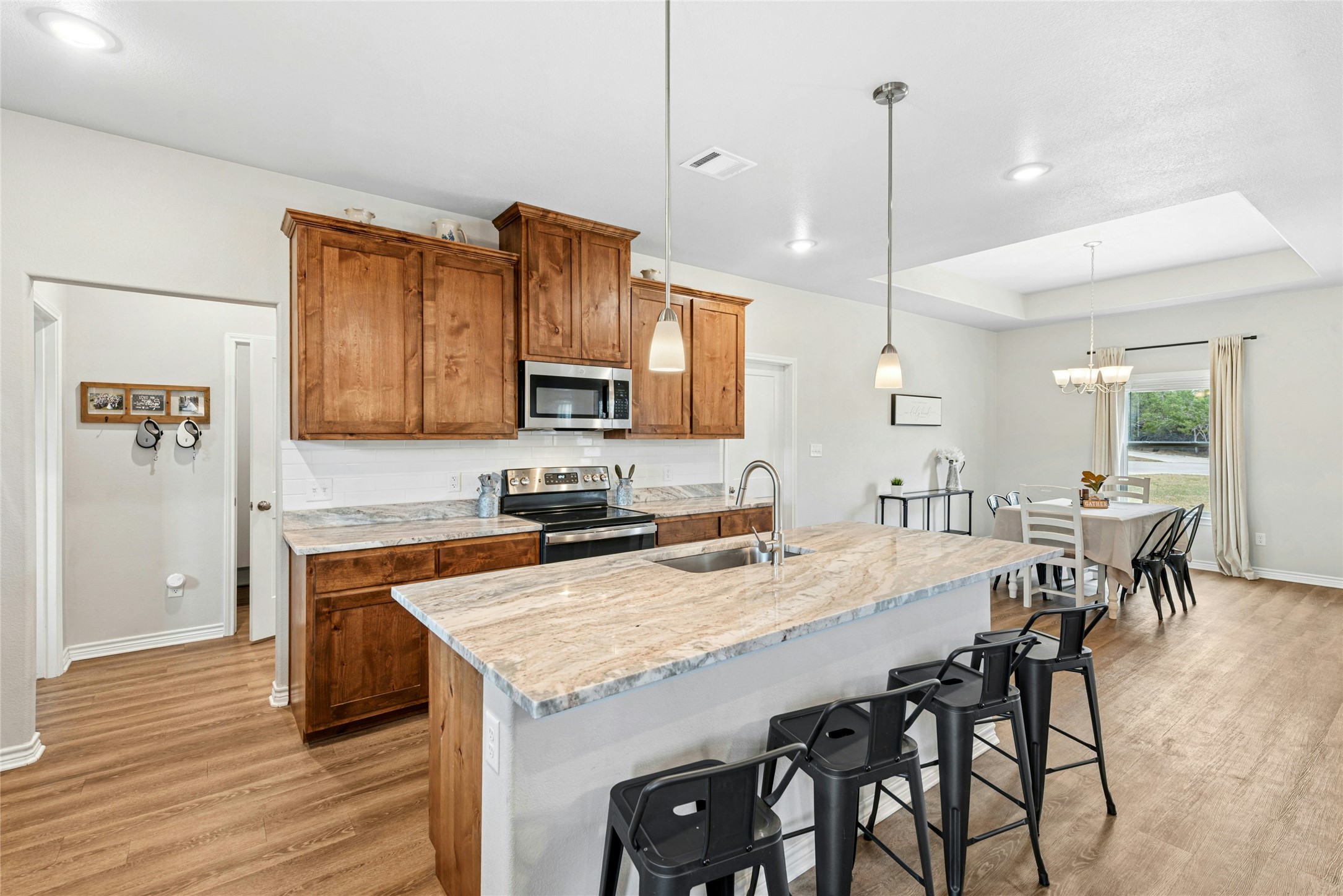 195 Rosebud Ranch Road Bertram, TX 78605 - Photo 15 of 40 a kitchen with granite countertop a table chairs stove and refrigerator