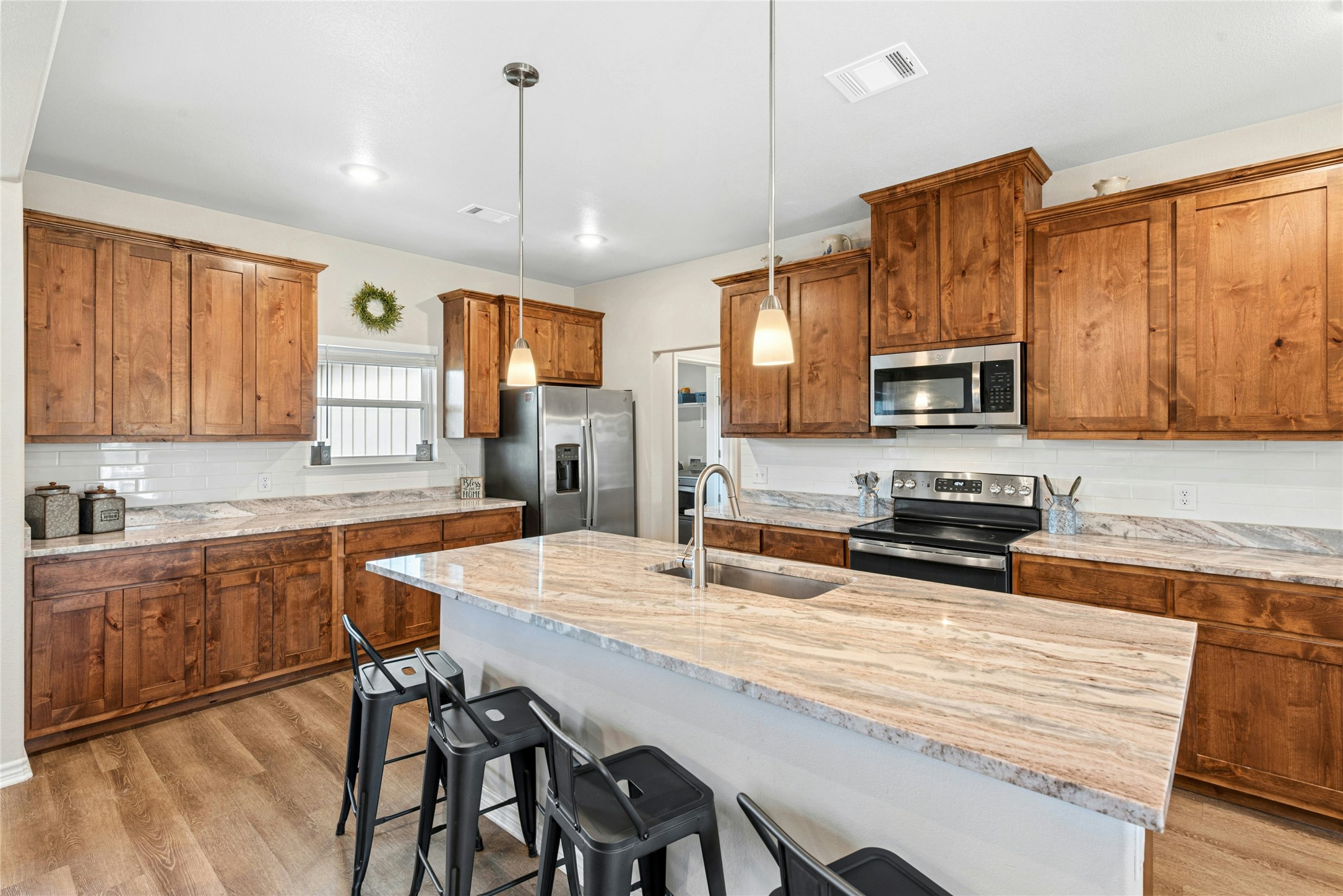 195 Rosebud Ranch Road Bertram, TX 78605 - Photo 16 of 40 a kitchen with stainless steel appliances granite countertop a stove a sink a microwave a refrigerator and cabinets