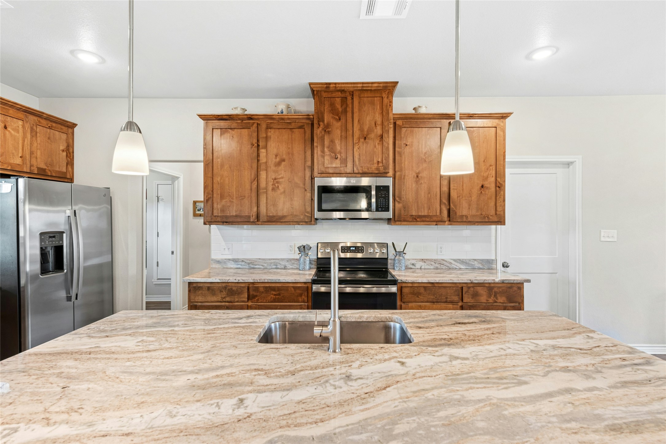 195 Rosebud Ranch Road Bertram, TX 78605 - Photo 19 of 40 a kitchen with stainless steel appliances kitchen island granite countertop a stove a sink and a refrigerator