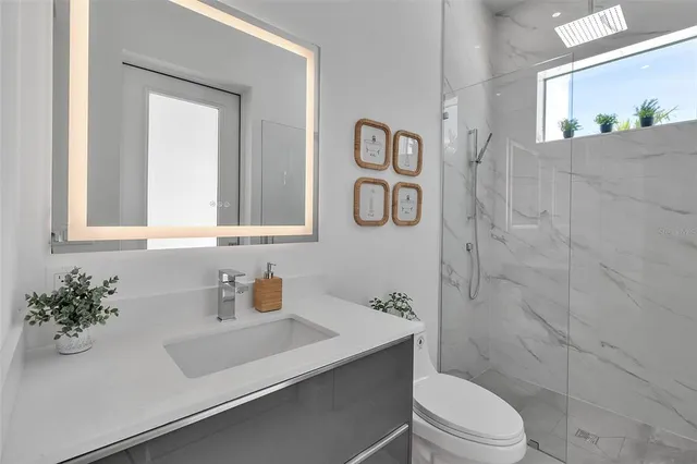 a bathroom with a toilet sink vanity and shower