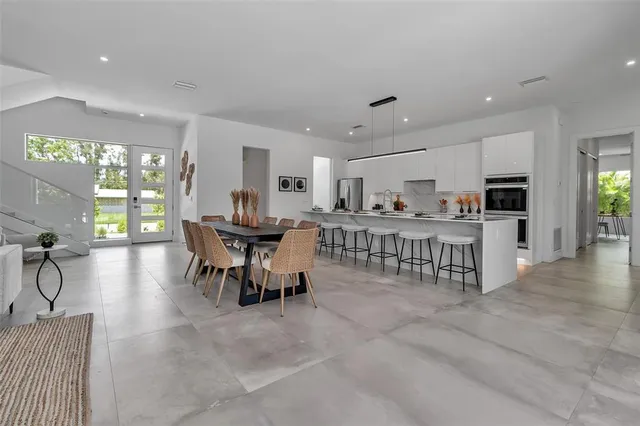 a kitchen with kitchen island granite countertop a stove a sink a oven a dining table and chairs