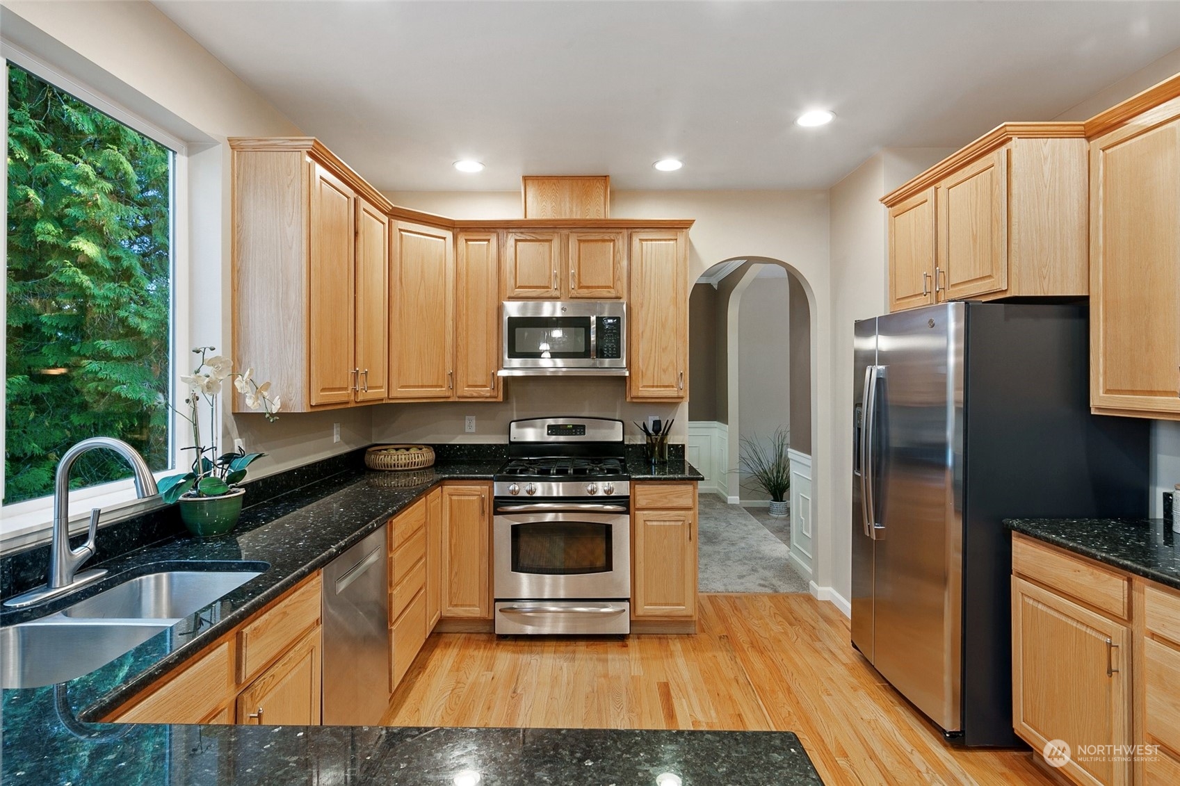 14704 Simonds Road Northeast Bothell, WA 98011 - Photo 8 of 40 a kitchen with stainless steel appliances granite countertop a refrigerator a stove top oven a sink and dishwasher with wooden floor