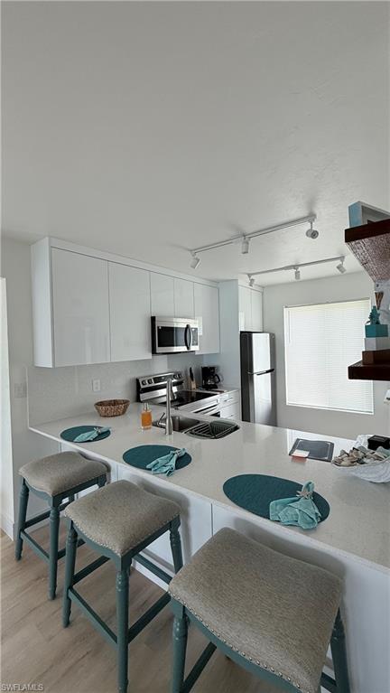 2235 San Marco Road, Unit 5204 Marco Island, FL 34145 - Photo 29 of 34 Kitchen featuring a large central island with seating, white cabinetry, stainless steel appliances, and track lighting