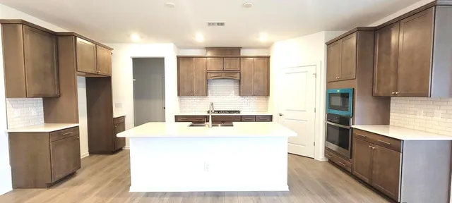 a large kitchen with stainless steel appliances granite countertop a sink and a refrigerator