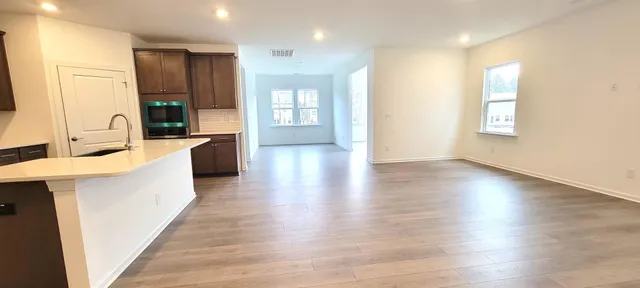 a large kitchen with stainless steel appliances a large counter top a sink a refrigerator and a window