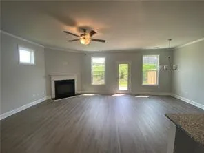 an empty room with wooden floor fireplace and windows