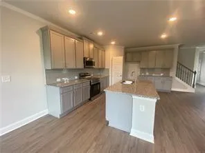 a kitchen with kitchen island granite countertop wooden floors stainless steel appliances a sink and a counter