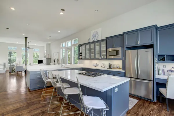 a kitchen with stainless steel appliances granite countertop a table chairs sink refrigerator and stove