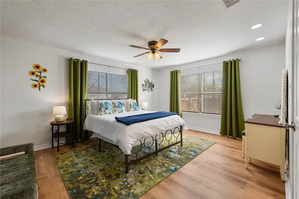 a spacious bedroom with a bed a dresser and wooden floor